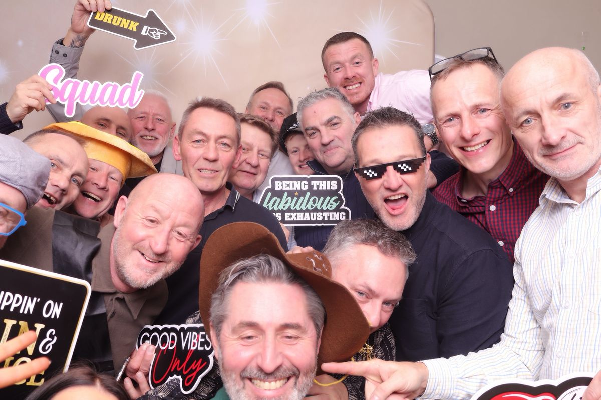A big group of guests squeezing into the photo booth with props